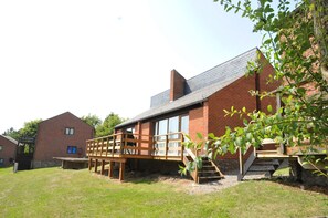 A brick building with a wooden deck and stairs leading to a windowed area.