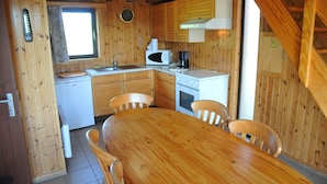 A wooden cabin with a kitchen area, a dining table, and four chairs. - Kangourou 2 (Hastiere)
