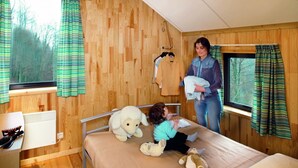 A cozy cabin room with wooden walls, a bed, and a window with curtains. - Kangourou 6 (Hastiere)