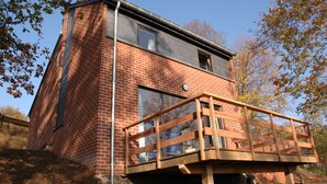 A two-story brick building with a wooden deck. - Kangourou 6 (Hastiere)