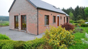 A brick house with a sloped roof, large windows, and a gravel driveway. - Laloux (Rochefort)
