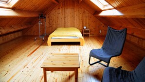 A cozy attic bedroom with a wooden floor, a bed, a chair, and a small table. - Laloux (Rochefort)