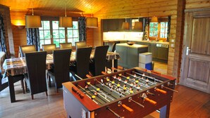 Una habitación acogedora con una mesa de futbolín, paredes de madera y un comedor con sillas y una mesa.