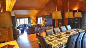Acogedor interior de una cabaña de troncos con comedor, cocina y sala de estar.