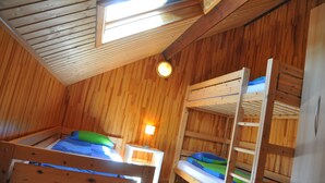 A wooden cabin with bunk beds, a skylight, and a small table with a lamp. - Lindbergh (Durbuy)