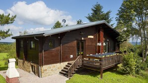 A wooden cabin with a stone foundation, a porch, and a chimney.