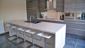 Eine moderne Küche mit einer großen Kochinsel, Barhocker, einer Spüle und eingebauten Geräten.