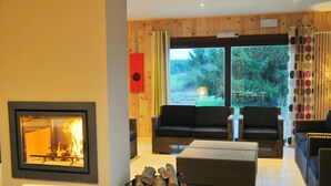 Een knusse woonkamer met een open haard, comfortabele zitplaatsen en uitzicht op de omgeving.