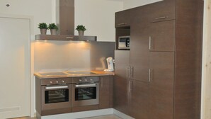 Een compacte keuken met ingebouwde apparatuur, waaronder een fornuis, oven en magnetron, en een ruime kast.