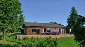 Een modern gebouw met een plat dak, grote ramen en een terras met buitenmeubilair.