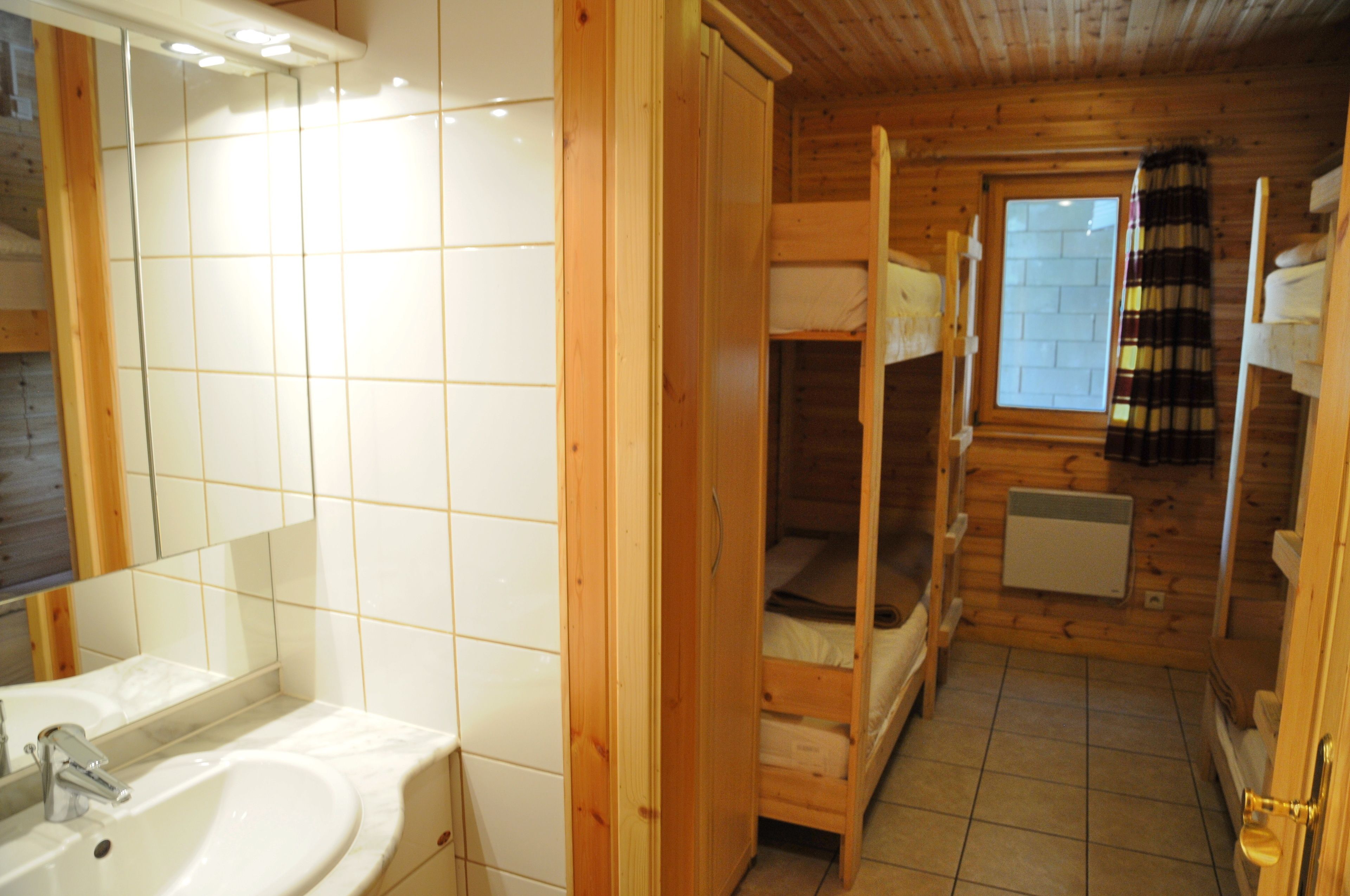Un baño estilo cabaña de madera con lavamanos, espejo y literas.