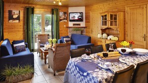 A cozy cabin interior with a dining area, a TV mounted on the wall, and wooden walls. - Rochettes - Vénus 1 (La Roche-en-Ardenne)