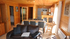 A cozy wooden cabin interior with a living area featuring a leather sofa, dining table, and chairs. - Rochettes - Vénus 2 (La Roche-en-Ardenne)