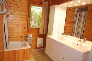 A wooden cabin bathroom with a bathtub, a sink, and a window with curtains. - Rochettes - Vénus 2 (La Roche-en-Ardenne)