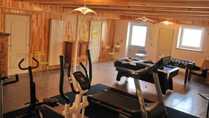 Uma academia com equipamentos de exercícios, incluindo esteiras, mesa de bilhar e mesa de pebolim.