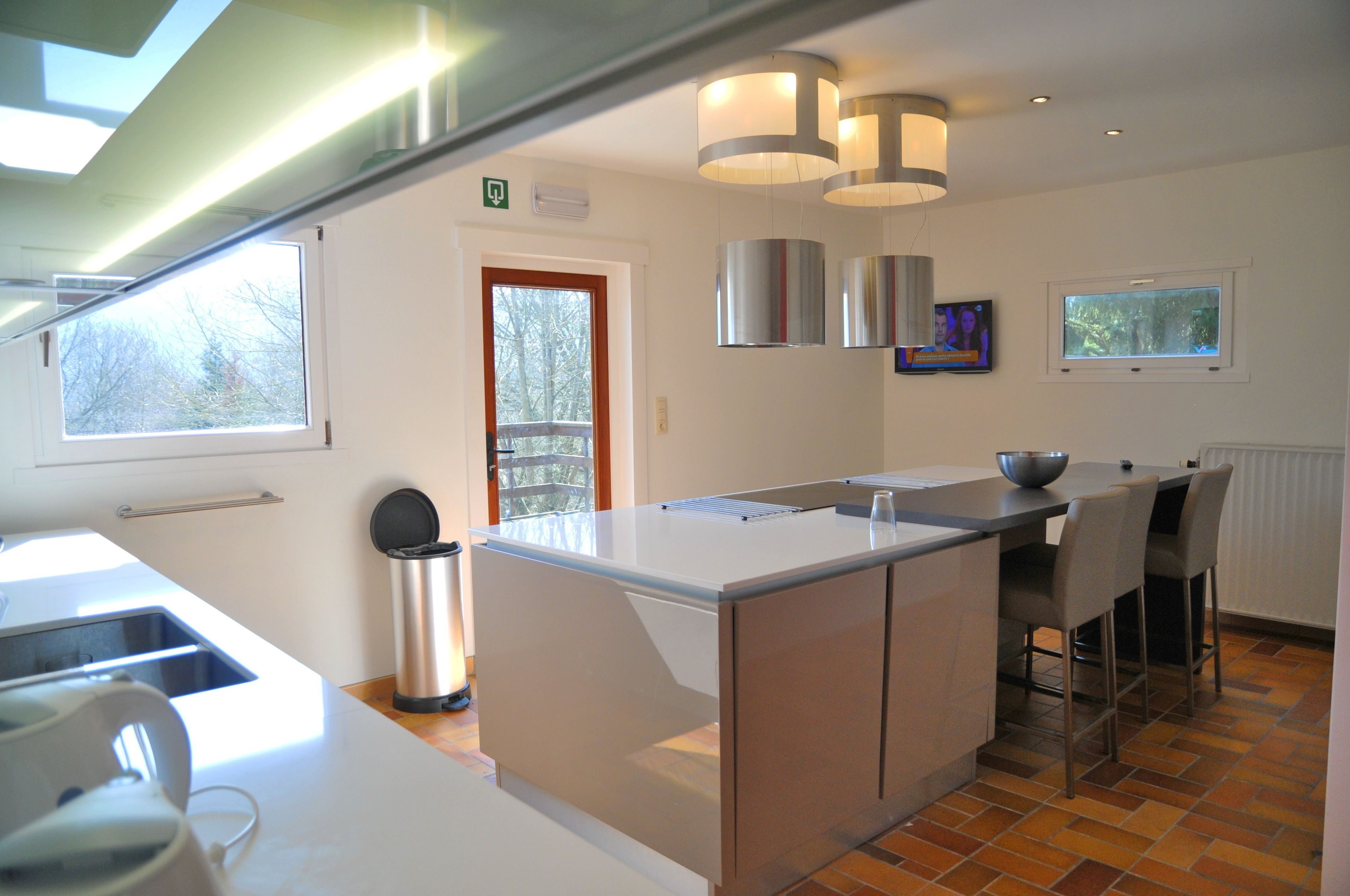 A modern kitchen with a central island, bar stools, and a view of the outdoors.