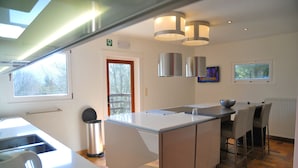 Een moderne keuken met een centraal eiland, barkrukken en uitzicht op de omgeving.