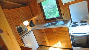 Una cocina compacta con armarios de madera, un fregadero, un microondas, una estufa y un refrigerador.