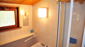 Un baño con techo de madera, ventana, lavamanos, espejo y ducha.