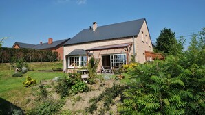 Een huis met schuin dak, grote ramen en een bakstenen gevel.