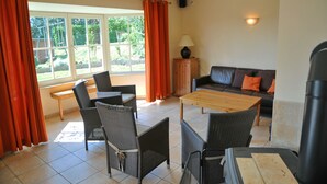 Een kamer met een bank, stoelen, een tafel en een raam met gordijnen.