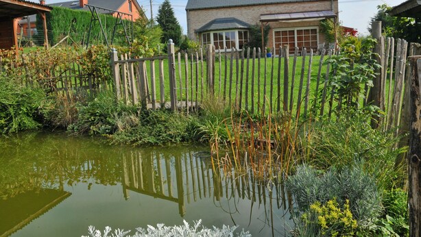 Een woonwijk met een huis, een houten omheining en een vijver.