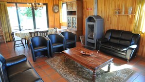 A cozy living room with a fireplace, leather sofas, a dining table, and a large window.