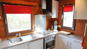 A compact kitchen with a stainless steel sink, a gas stove, and white cabinets. - Wapiti (Houyet)