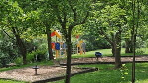 Un parque infantil con estructuras de juego coloridas, rodeado de árboles y césped.