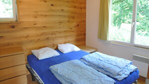 Una habitación con paneles de madera, una cama, un ventanal y un radiador.