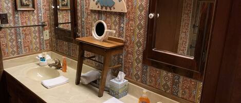 Une salle de bain avec deux lavabos, un meuble-lavabo en bois, un miroir et un panneau décoratif.