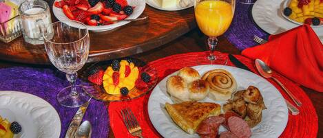 A breakfast setting with plates of fruit, pastries, and a glass of orange juice.