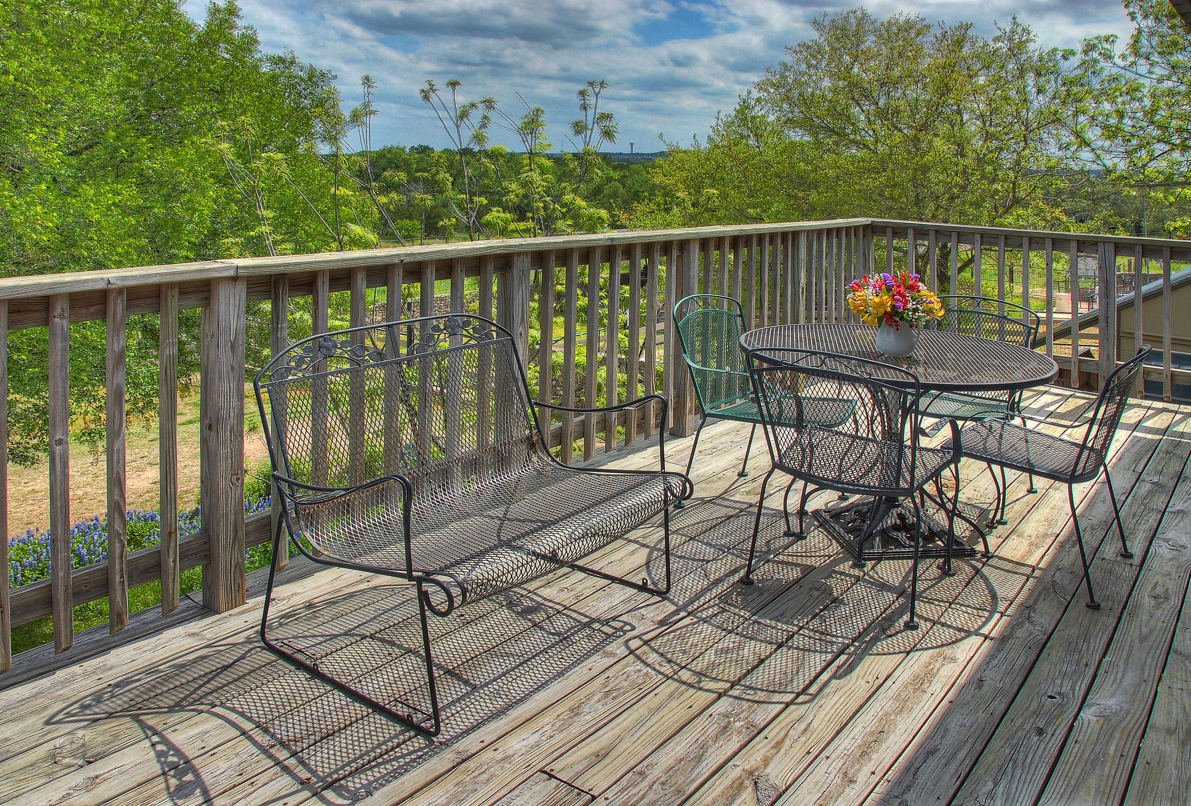 A wooden deck with metal chairs and a table, surrounded by a wooden railing.