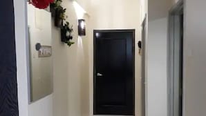 A hallway with a black door, a red flower decoration, and a small mat on the floor. - SUNSET View Studio Apartment (Langkawi)