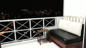 A balcony with a white railing, a wooden bench, and a white sofa. - SUNSET View Studio Apartment (Langkawi)