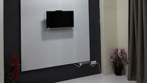 A modern living room with a mounted TV, ceiling fan, and a potted plant. - SUNSET View Studio Apartment (Langkawi)