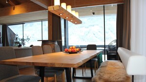 Uma sala de jantar moderna com uma mesa de madeira, cadeiras estofadas cinzentas e um banco com um cobertor de pele.