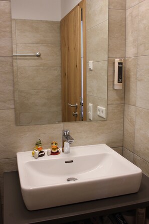 Un baño con un lavamanos blanco, una puerta de madera y un espejo.