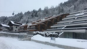 Estância de esqui com edifícios de madeira, teleférico e árvores cobertas de neve.