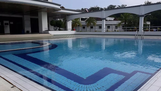 Una piscina con plataforma de baldosas y zona cubierta.