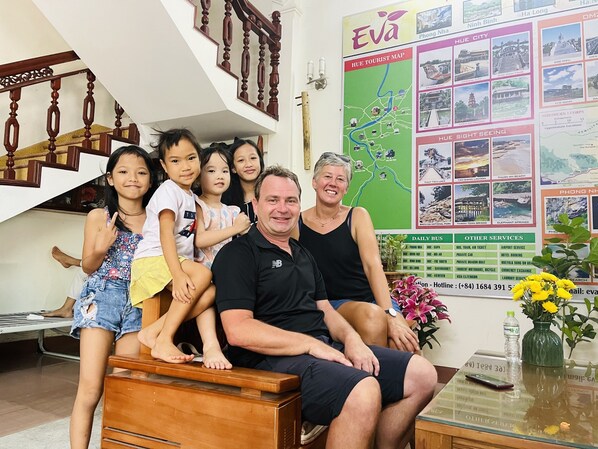 A family sitting on a wooden bench in a room with a staircase and a wall map.