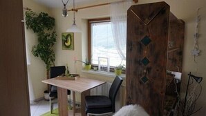 Un coin repas avec une table et des chaises en bois, une plante en pot et une fenêtre avec des rideaux.