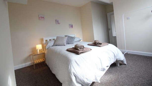Een slaapkamer met een bed, nachtkastje en een spiegel.