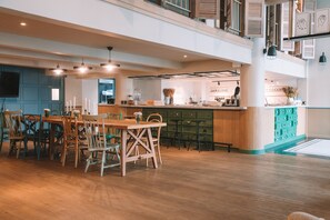 A spacious dining area with a wooden table and chairs, a kitchen area with a bar, and a view of the city. - The Blanket Hotel (Phuket)