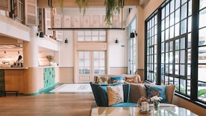 A spacious lobby with a seating area, a reception desk, and large windows offering a view of the street. - The Blanket Hotel (Phuket)