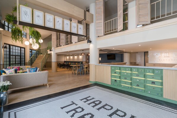 A spacious, multi-level interior with a central staircase, a dining area, and a kitchen with green cabinetry. - The Blanket Hotel (Phuket)
