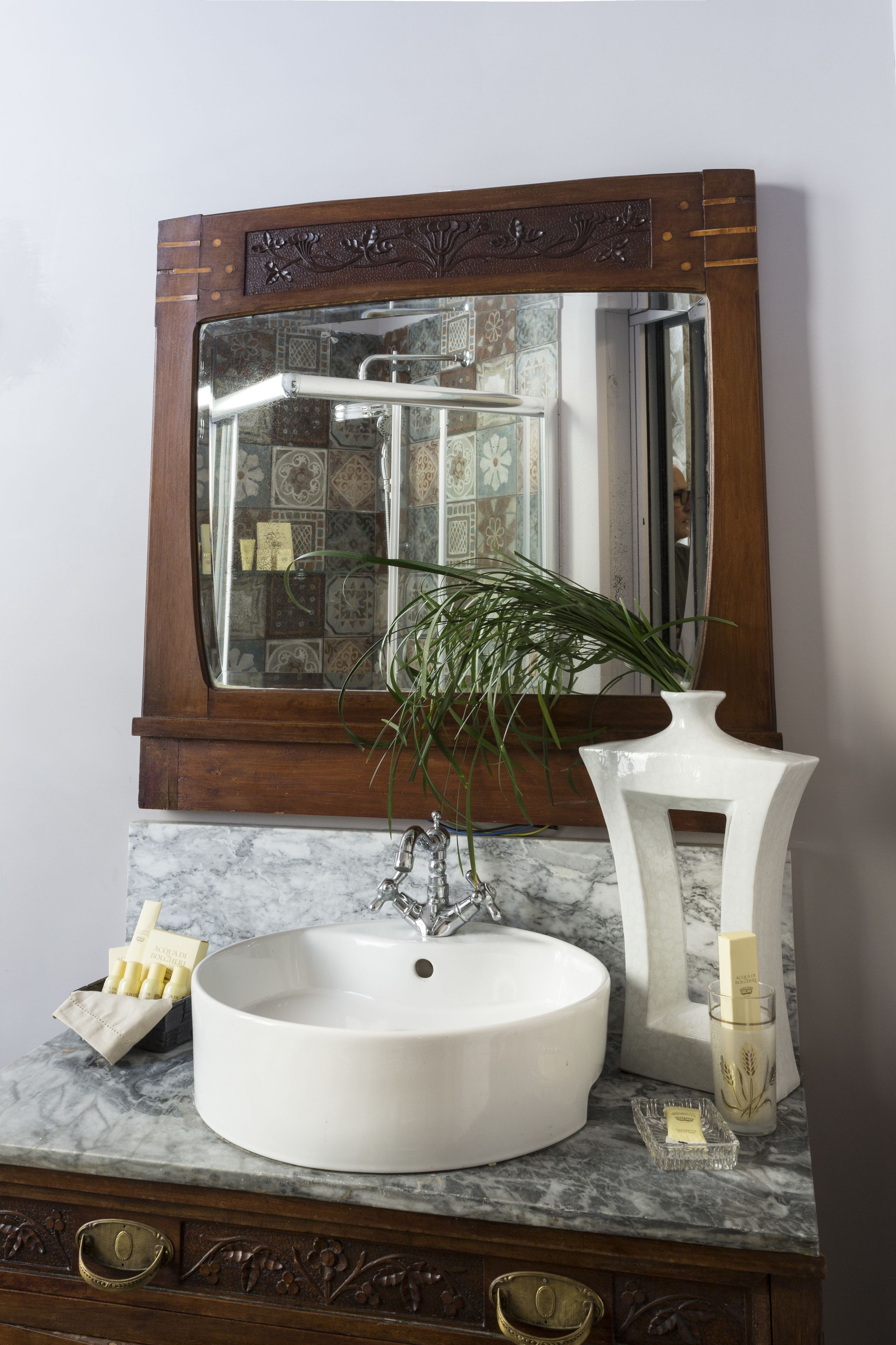 Un baño con un lavamanos blanco, un espejo y una planta decorativa.
