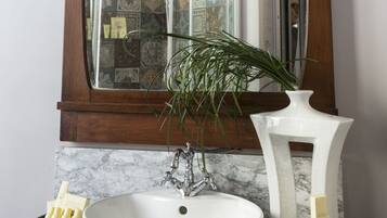 Un baño con un lavamanos blanco, un espejo y una planta decorativa.
