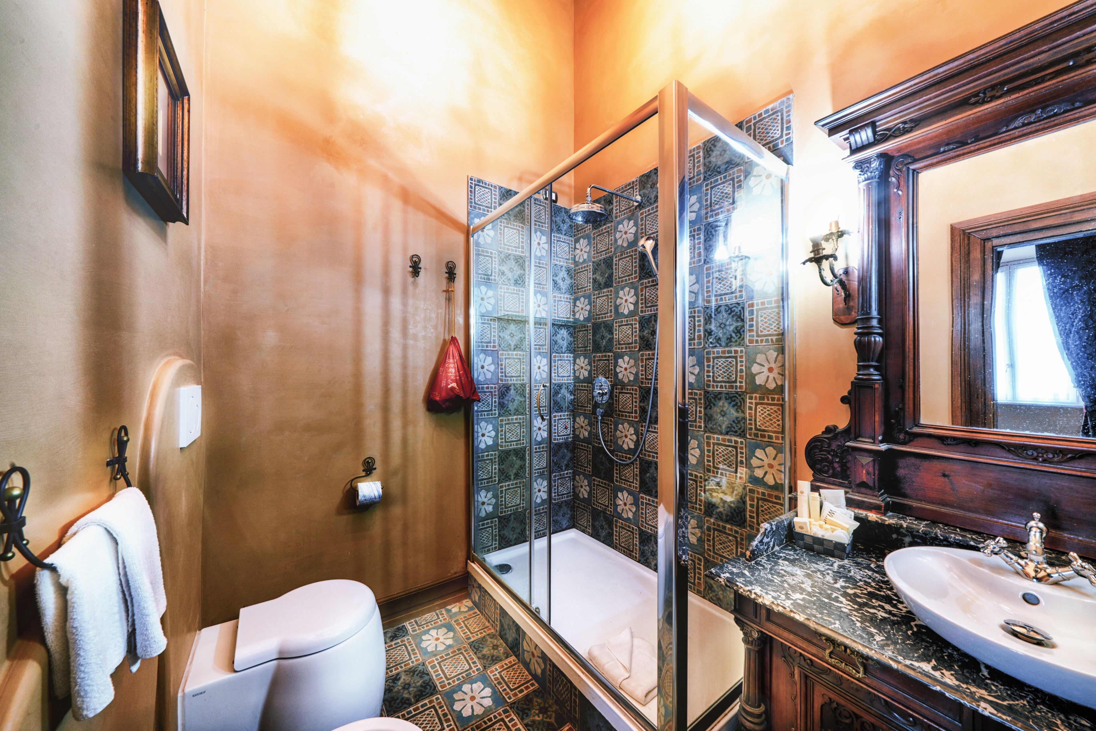Un baño con cabina de ducha de vidrio, un inodoro blanco, un lavabo con encimera de mármol y un espejo sobre el lavabo.