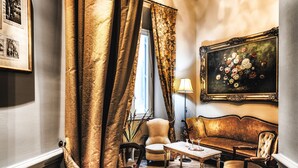A room with a sofa, chairs, a table, and a painting on the wall. - Navona Grand Suite (Rome)